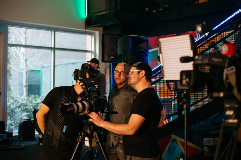 Camera crew setting up studio lighting and filming scene for types of video production for business.