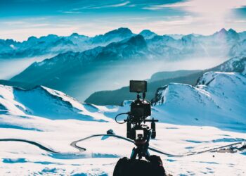 Camera on tripod filming snowy mountain landscape