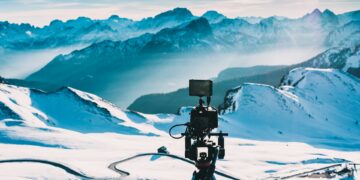 Camera on tripod filming snowy mountain landscape