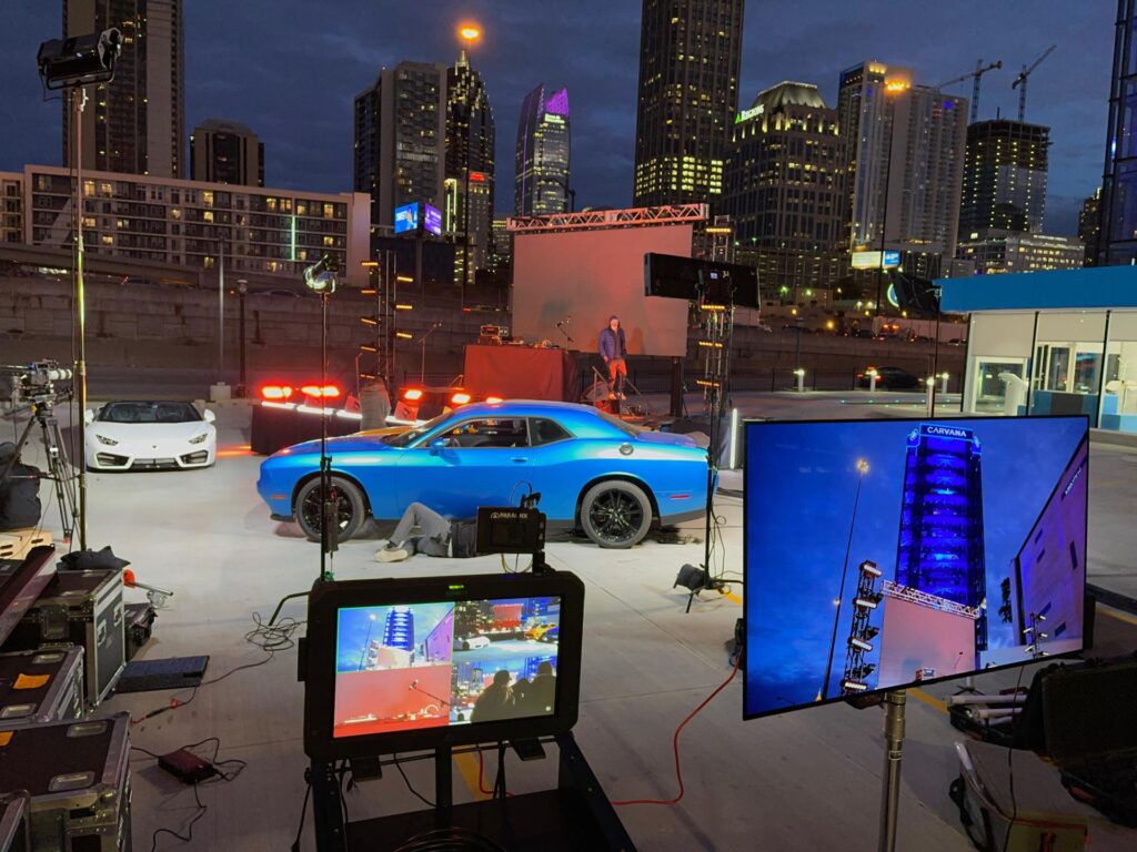 Behind-the-scenes setup of a cityscape tv commercial shoot with lighting, screens, and camera gear.ht